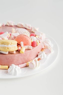 pembe kek buttercream, şekerleme ve macarons beyaz plaka üzerinde