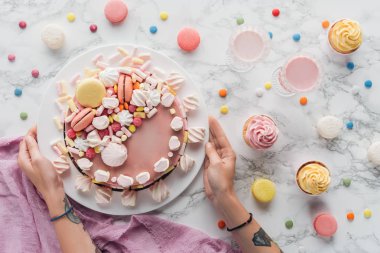 pembe Doğum günü pastası, şeker, tatlı çörekler ve milkshake dövmeli elleriyle kırpılmış görünümünü mermer masada 