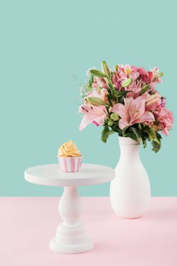 kek standı ve lily buket cam vazo içinde sunulan bir cupcake 