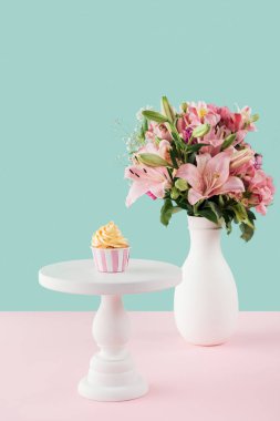 one cupcake on cake stand and bouquet of lily flowers in vase  clipart