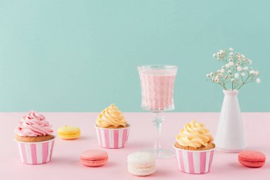 çörekler ve tatlı macarons ve pastel arka plan üzerinde milkshake bardak 