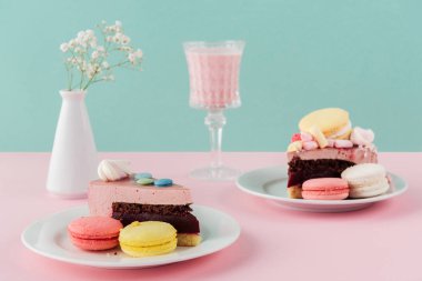 macaroons ve plakaları milkshake cam vazoda çiçekler ile dilim kek 