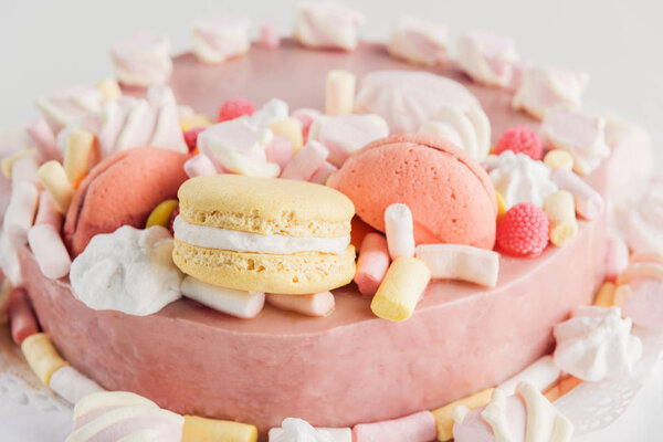 close up of pink cake with marshmallows and macarons 