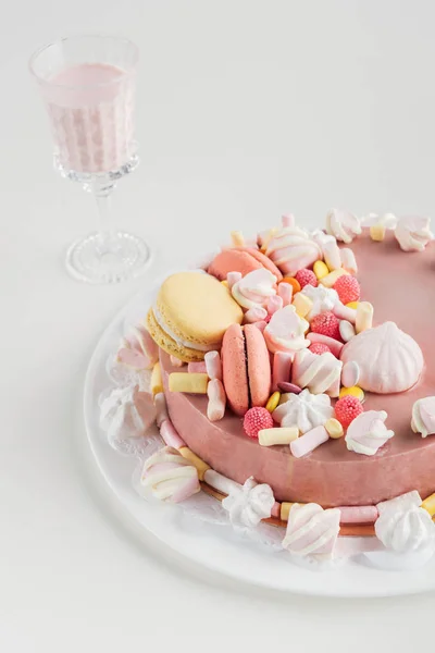 pink cake with marshmallows and macarons on plate and milkshake in glass