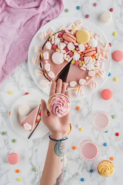 Abgeschnittene Ansicht Tätowierter Hände Mit Cupcake Über Marmortisch Mit Rosa — kostenloses Stockfoto