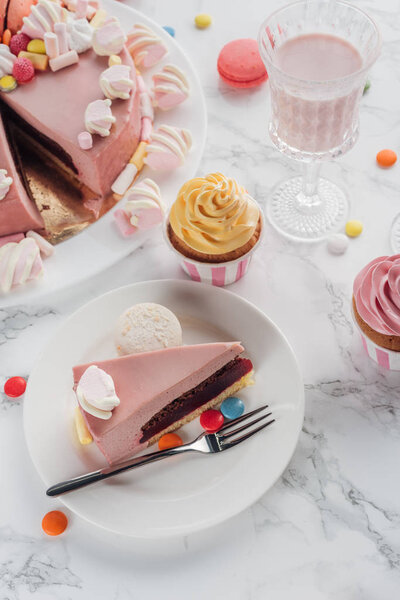 high angle view of birthday cake and cupcakes and milkshake in glass on table 