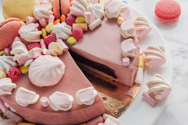close up of pink birthday cake with marshmallows, macarons and candies