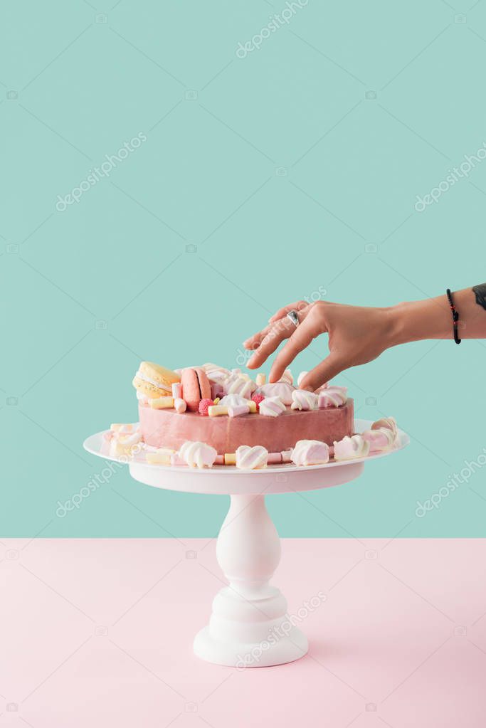 cropped view of woman taking marshmallow from sweet cake on stand