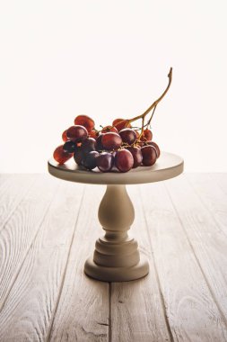 close-up shot of branch of grapes on stand on wooden table clipart