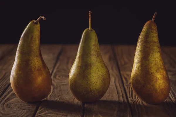 黒の素朴な木製のテーブルの行に熟した梨のクローズ アップ ショット — ストック写真