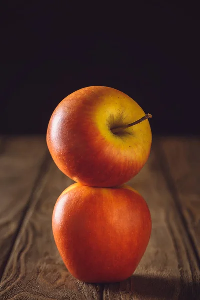 Close-up shot dari ditumpuk apel merah di meja kayu pedesaan di atas hitam — Stok Gambar Close Shot Dari Ditumpuk Apel Merah Meja Kayu Pedesaan Atas Stok Foto