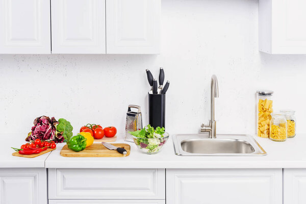 cherry tomatoes and bell peppers on cutting boards in light kitchen 