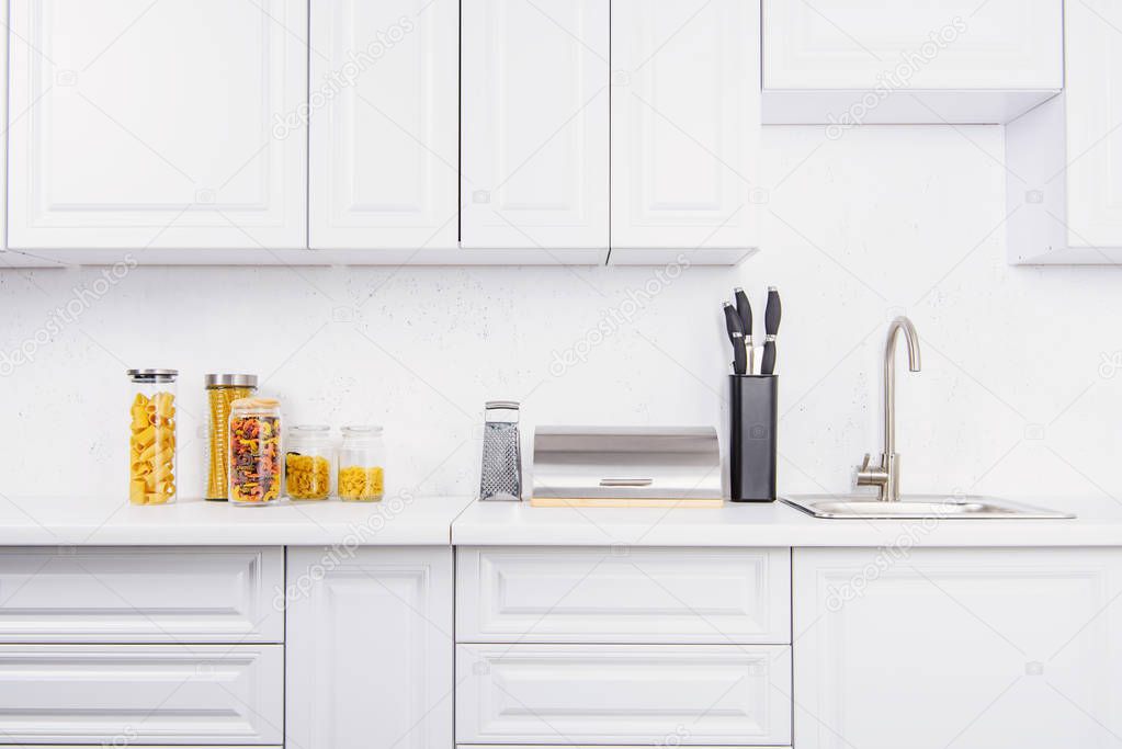 different types of pasta in glass jars in light kitchen