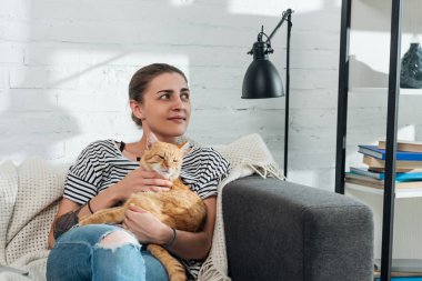 güzel genç kadın holding kırmızı kedi gülümseyen ve uzakta ev arıyorum
