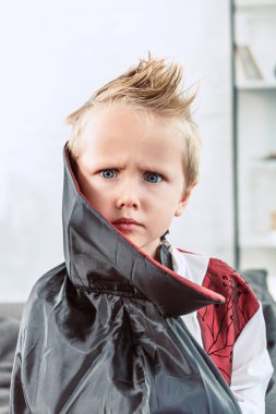 portrait of little boy in vampire halloween costume looking at camera at home clipart