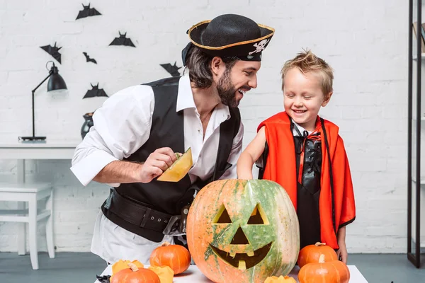 快乐的人在海盗服装和儿子在吸血鬼万圣节服装与南瓜一起在家里 — 图库照片