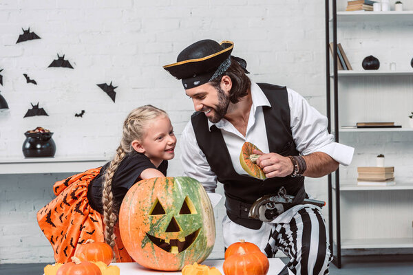 отец и дочь в костюмах на Хэллоуин вместе ищут тыкву дома
