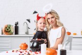 anya és lánya halloween jelmez asztalnál édességek fekete pot otthon a konyhában portréja