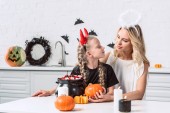 anya és lánya halloween jelmez asztalnál édességek fekete pot otthon a konyhában portréja