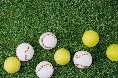Tenis ve beyzbol topları yeşil çimenlerin üzerinde düzenleme ile düz lay