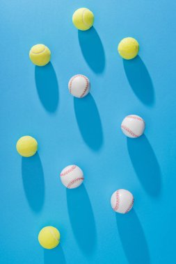 top view of arranged tennis and baseball balls on blue backdrop clipart