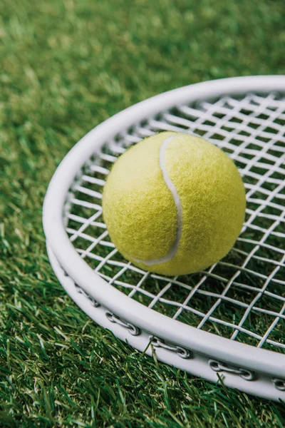 緑の芝生の上に横たわるラケットとテニスボールのビューをクローズ アップ — ストック写真