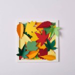 Flat lay with handcrafted paper leaves and frame on white tabletop