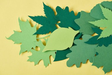 full frame of green handcrafted paper foliage arranged on yellow backdrop clipart