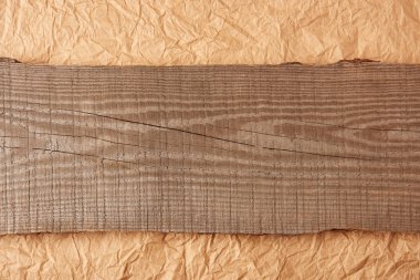 top view of wooden plank on crumpled paper backdrop clipart