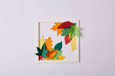 flat lay with handcrafted paper leaves and frame on white tabletop clipart