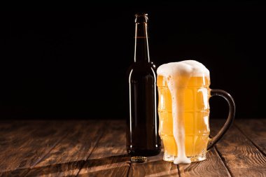 bardak bira dışarı akan köpük ve şişe bira ahşap masa, minimalist kavramı ile 