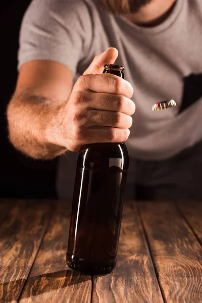 Gedeeltelijke Weergave Van Man Openen Bierflesje Houten Tafel — Stockfoto