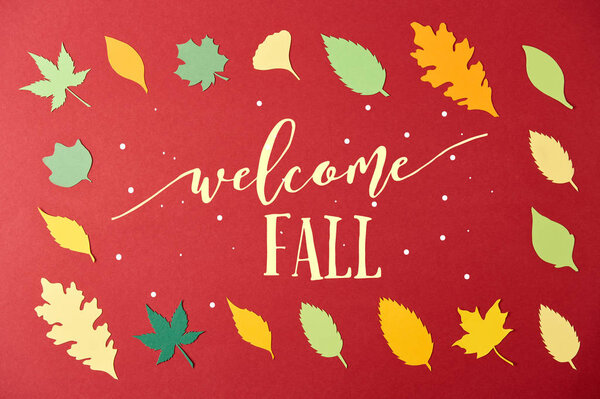 frame made of colorful papercrafted leaves with "welcome fall" lettering on red background