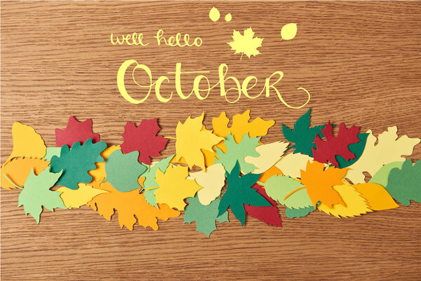 top view of colorful papercrafted foliage with "well hello october" lettering on wooden background