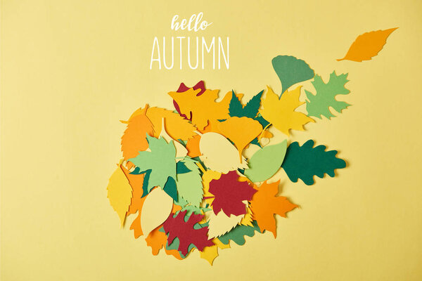 flat lay with colorful papercrafted foliage with "hello autumn" lettering on yellow background