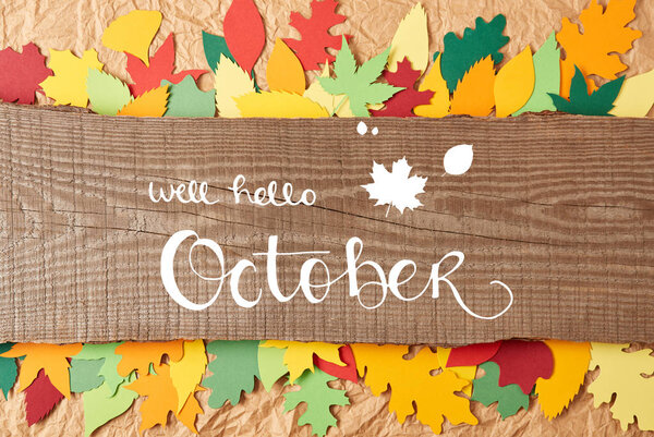 top view of wooden plank with "well hello october" lettering and colorful paper leaves arrangement on crumpled paper backdrop