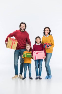 Ebeveynler ve çocuklar üzerinde beyaz izole kamera bakarak sarılmış hediyeler ile gülümseyen 