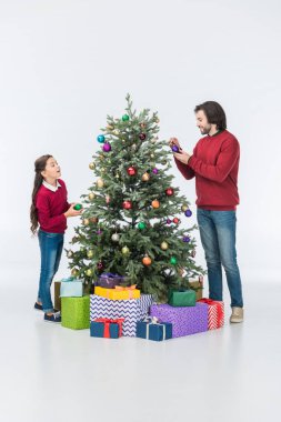 Baba ile kızı dekorasyon Noel ağacı üzerinde beyaz izole cam topları ile gülümseyen