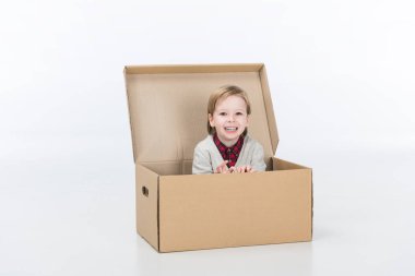 smiling boy sitting in cardboard box isolated on white clipart