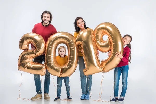 Mutlu aile yeni yıl için altın 2019 tabelasını tutuyor ve beyaz kameraya bakıyor. 