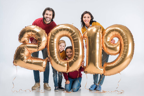 smiling parents with siblings holding sign 2019 made of golden balloons for new year isolated on white background 