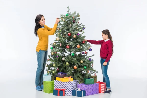 Anne ile kızı dekorasyon Noel ağacı üzerinde beyaz izole cam topları ile gülümseyen