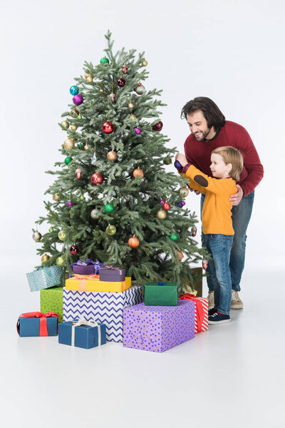 smiling father with son decorating christmas tree with presents isolated on white