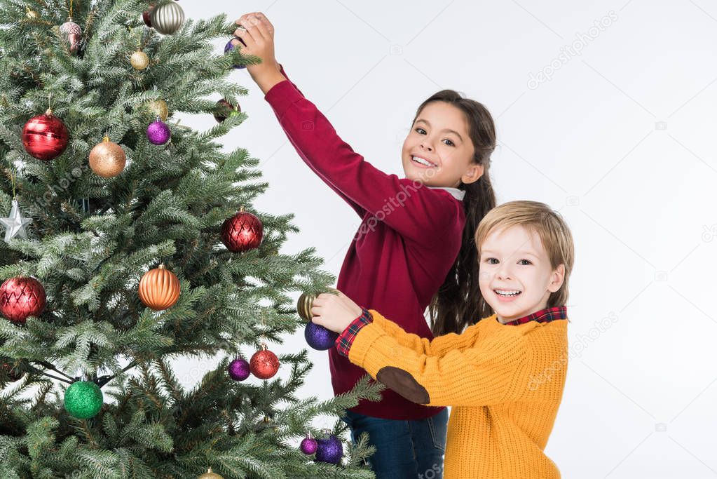 Happy siblings decorating christmas tree with glass balls isolated on white