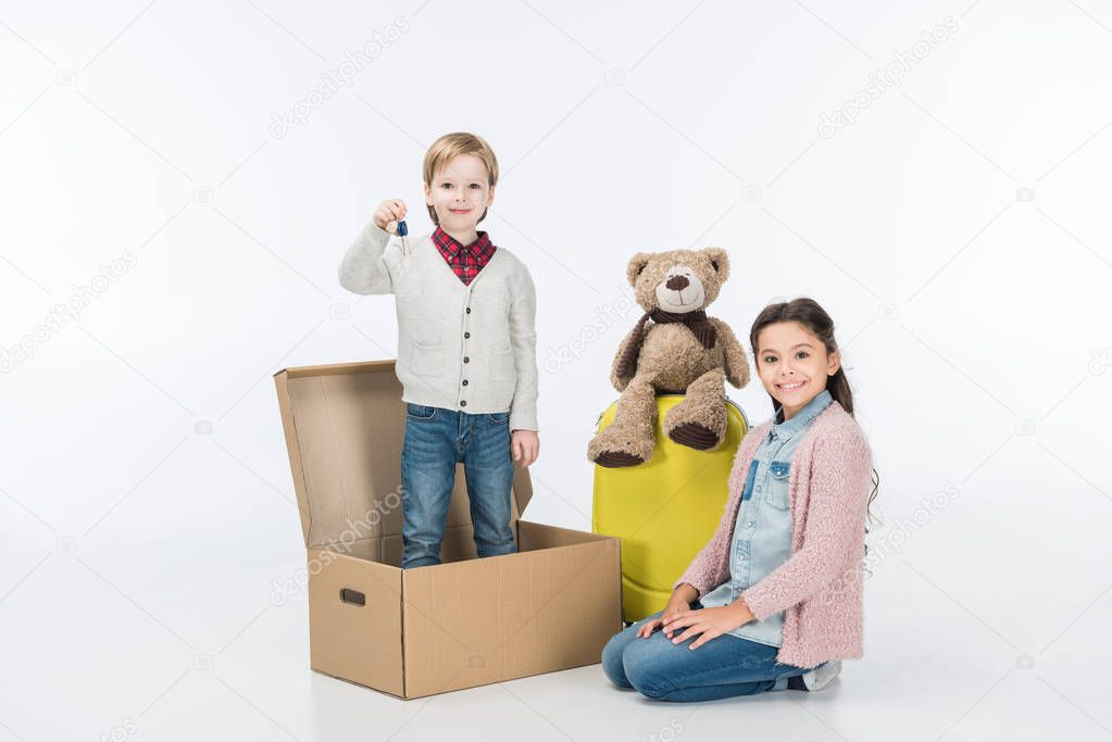 Little boy holding key from new house ready to move with his sister into new house isolated on white 