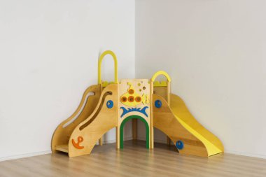 beautiful bright wooden slides in playing room at kindergarten clipart