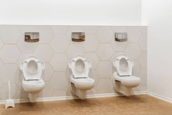 clean white toilet bowls in toilet in modern kindergarten 