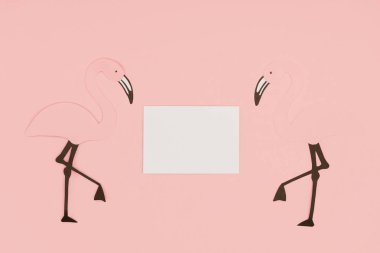 close-up view of blank white card and papercut flamingos isolated on pink clipart