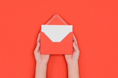 partial top view of person holding red envelope with blank white card isolated on red clipart