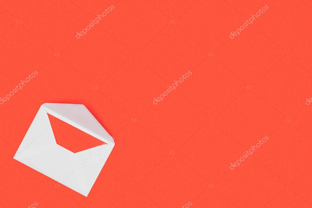 Top view of open white envelope with red card isolated on red background